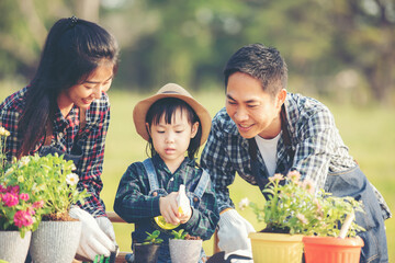 Family child girl helping parent care plant flower in garden. Young people mother, father and...