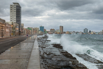 Big waves on Malecon streets during sunrise with storm clouds in background. Havana, Cuba