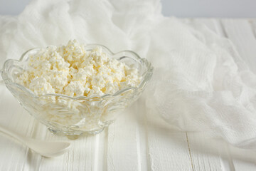 Cottage cheese in a glass bowl. On a white wooden table