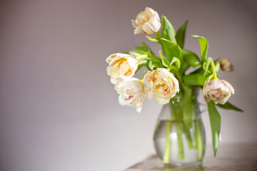 Bouquet of tulips in glass vase under the table. Copy space.