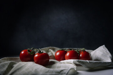 Red tomatoes with green leaves on dark background