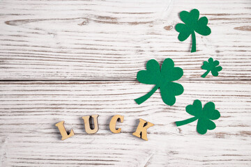 Word luck and shamrock clover leaves on a white wooden background. Happy St. Patrick's Day. Irish...