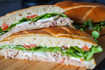 Sandwich with tuna and vegetables on wooden board.