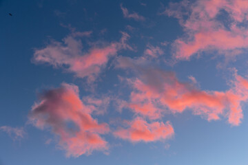 Pink glows clouds from the sunset. Sky pattern background.