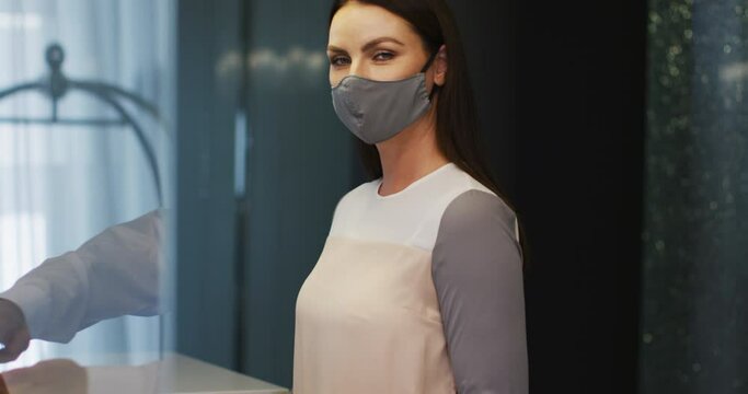 Caucasian woman wearing grey face mask looking at the camera and smiling