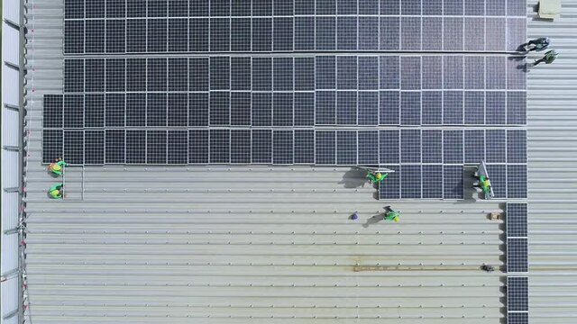 top view worker installing a solar cell on the factory roof.	