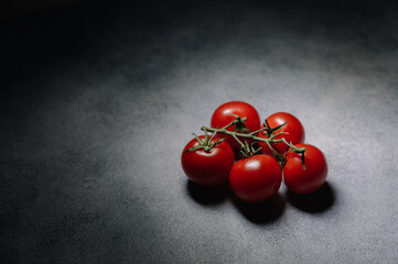 bunch of red tomatoes with green leaves on gray background
