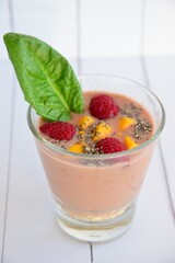 smoothie in glass with raspberry, mango, chia seeds and spinach