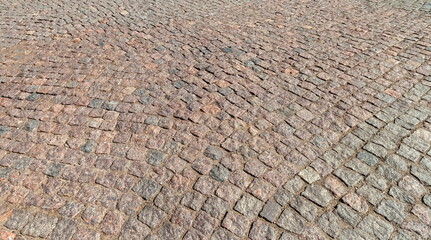 Stones laid close to each other (paving stones) as road surface in summer