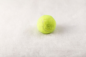 A yellow lawn tennis ball on a white carpet.