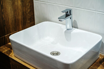 White ceramic washbasin and chrome-plated faucet in the bathroom interior. Close-up