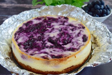 Homemade swirl blueberry cheesecake on dark wooden background