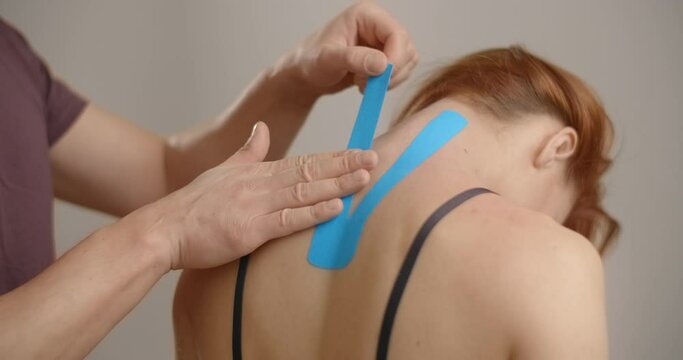 Kinesiologist sticks tapes to the neck of female patient, recovery of an athlete after injury, kinesiotapes in the therapy of osteochondrosis, , 4k 60p Prores HQ 10 bit