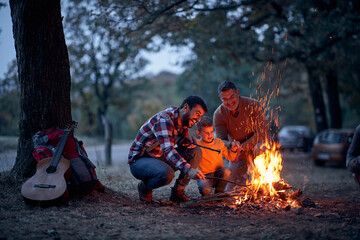 Boy with father and grandfather preparing campfire - obrazy, fototapety, plakaty