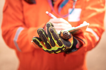 Close-up action of safety supervisor's hand which is weared an impact glove is holding a clipboard,...