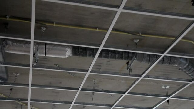 Tilting over bare suspended ceiling frame on construction site