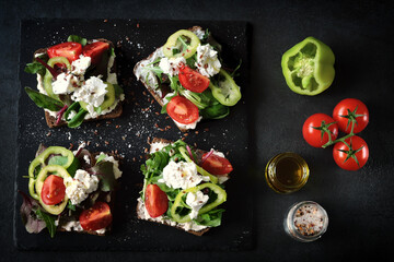 Healthy open sandwiches with salad and white cheese on a black background. The keto diet. Keto snack.