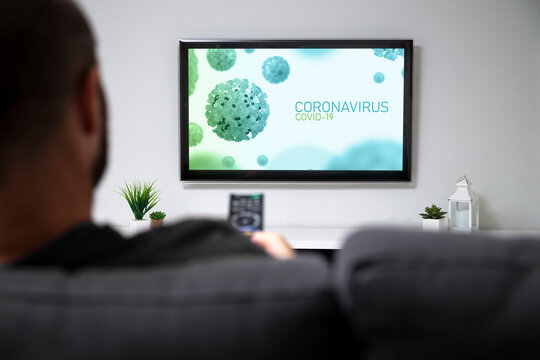 TV Screen With Covid-19 Coronavirus News. Man In The Sofa Of His Home Watching A Graphic Of Covid In The Television. Control Remote In The Hand.