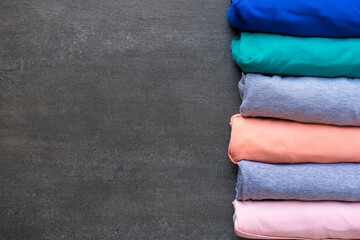 close up of rolled colorful t shirt clothes on black table background