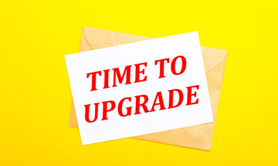 On a yellow background, an envelope and a card with the text TIME TO UPGRADE. View from above