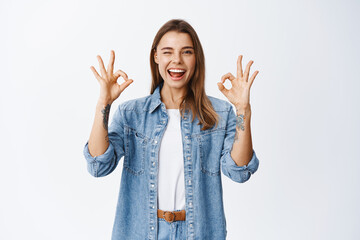 All good. Smiling excited girl showing okay signs and winking, say yes or alright, praise great...