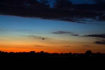 Sunset over field and city silhouette