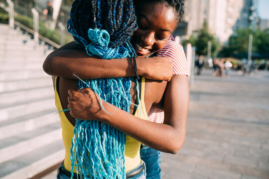 Two young black female siblings outdoor hugging positive
