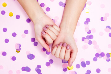 Obraz na płótnie Canvas Elegant nude manicure on a pink background with confetti