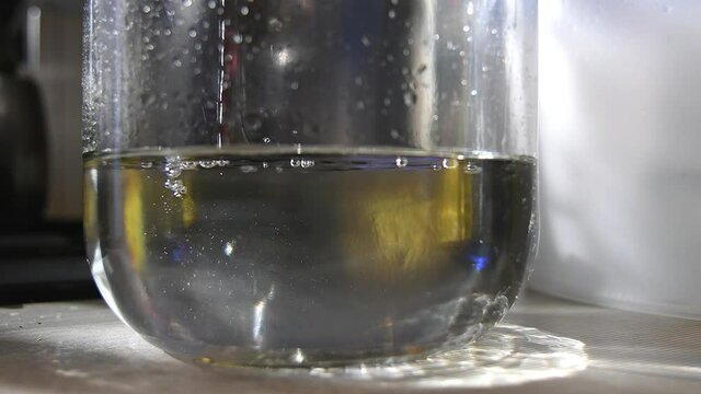 Moonshine flows in a thin stream into the jar during distillation. Moonshiner prepares strong alcohol at home. 