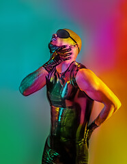 Multicolored creative artistic portrait of a rubber fetish, latex young man with fashion leather outfit on a colorful rainbow lighting and background. - obrazy, fototapety, plakaty