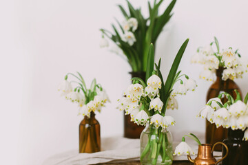Hello spring. Spring white flowers in retro glass bottles on rustic linen cloth and wood in room.
