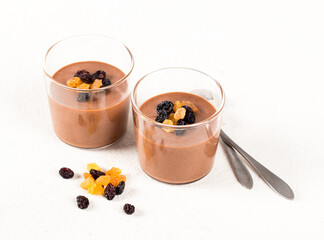 Creamy pudding made of gold and black raisins in a glass on a white background
