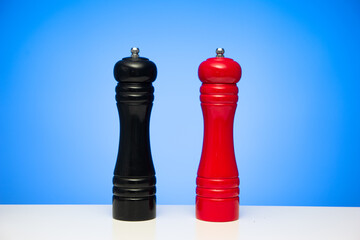 Wooden black pepper and red ground salt grinder mill isolated on blue background