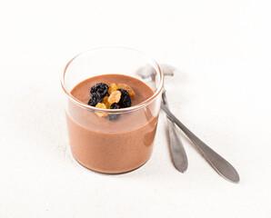 Energy dessert, Panna Cotta made of gold and black raisins in a glass on a white background