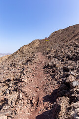 Rocky and stony mountain trail in Hatta Hajar Mountains (Hatta mountain sign hike), with directional signpost, United Arab Emirates.