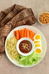 Gado-gado, traditional Indonesian salad with peanut sauce on brown background