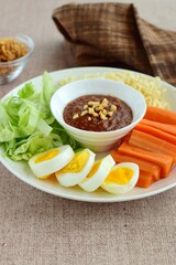 Gado-gado, traditional Indonesian salad with peanut sauce on brown background