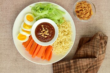 Gado-gado, traditional Indonesian salad with peanut sauce on brown background