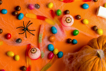 Halloween holiday concept. Many sweets on an orange background