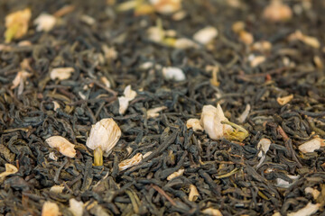 Texture of dry green tea leaves with jasmine petals. Soft focus in the foreground and background of the image