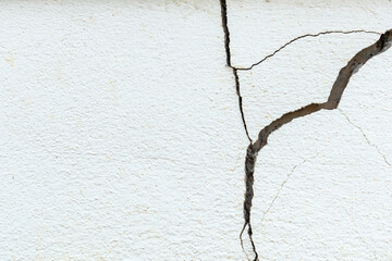 A house white wall with a large crack. Grunge concrete cement white wall with a crack in an...