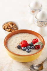 Healthy breakfast - oatmeal with berries and nuts in a bowl on the table.
