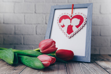 Photo frame with pink hearts and pink tulips on a brick wall background. spring concept