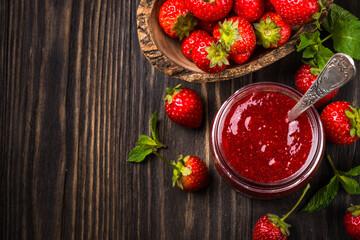 Strawberry jam in the glass jar with fresh berries at wooden table. Top view with copy space.