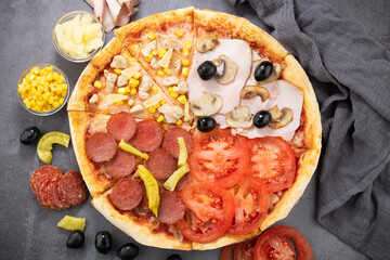 pizza and pizza ingredients. Olives, mushrooms, salami, tomato, pineapple and pizza on a dark background. Top view