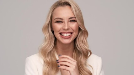 A surprised young blonde businesswoman is looking to the camera standing isolated over gray background in studio - Powered by Adobe