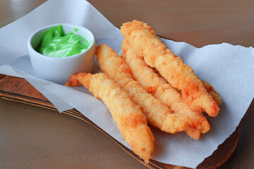 Prawns in batter with sauce on a wooden background.