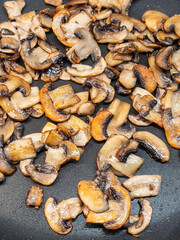 Close up of fried cut mushrooms in pan, top view.