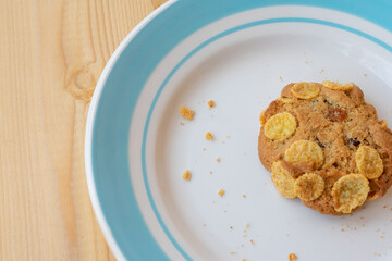 Cereal cookie in plate on wooden table. Crunchy fresh baked cookie with crumbs.
