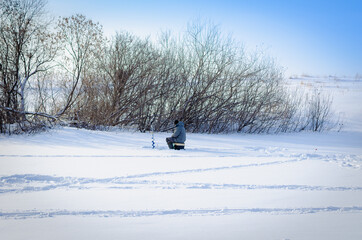 Lonely fisherman on a winter pond.